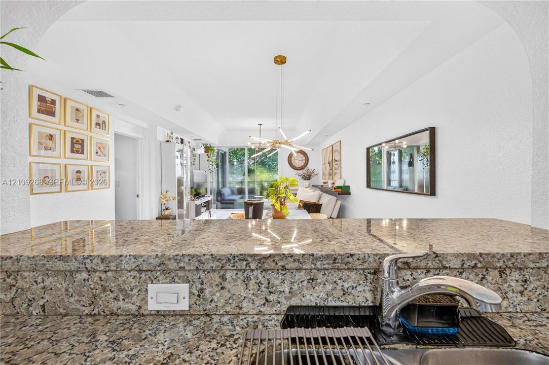 Stone countertop featuring a polished finish, stainless steel faucet, and arched ceiling entry
