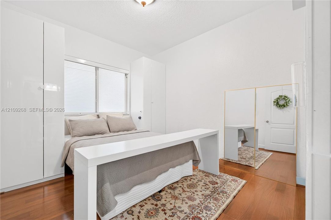Room featuring high-gloss white built-in cabinetry, wood-finish flooring, a flush-mount ceiling light, and a white interior door