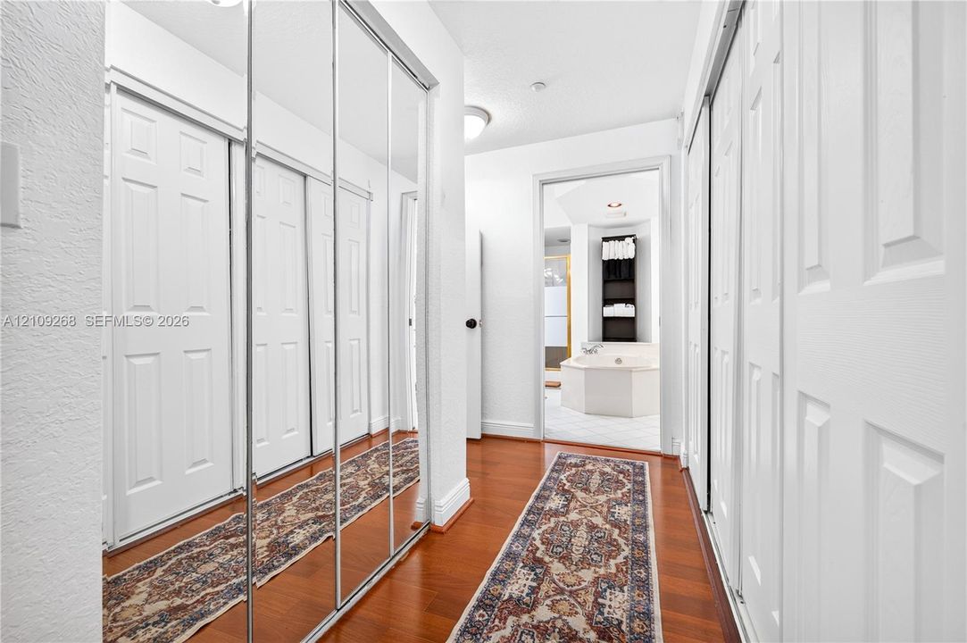 Hallway featuring wood-finish flooring, floor-to-ceiling mirrored sliding closet doors, and recessed lighting