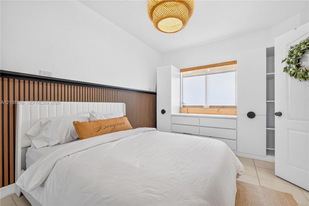 Vertical wood-slat accent wall, built-in white cabinetry, custom window trim, and a textured pendant light fixture