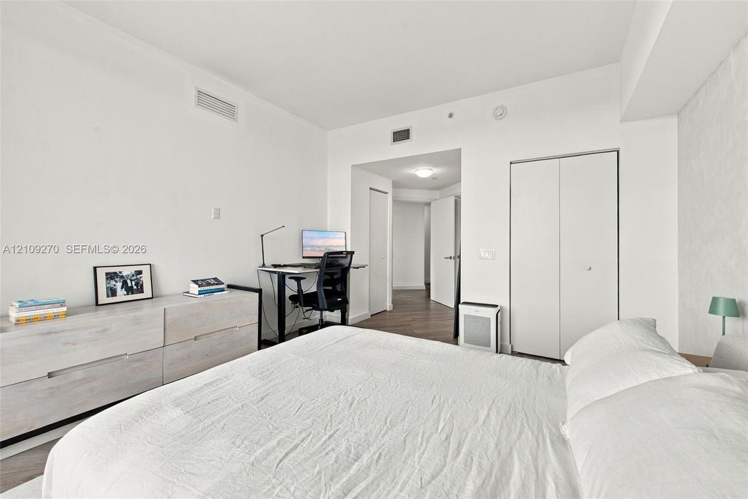 Room featuring wood-finish flooring, white walls, and a closet with double-panel doors