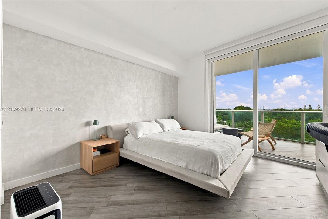 Textured accent wall, floor-to-ceiling glass sliding doors, private balcony, and wood-finish tile flooring