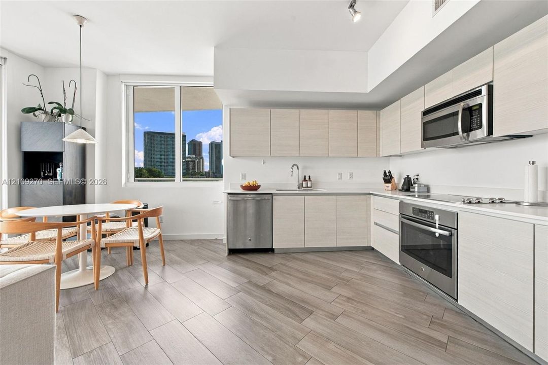 Kitchen featuring light-toned cabinetry, stainless steel appliances, wood-finish flooring, and expansive windows