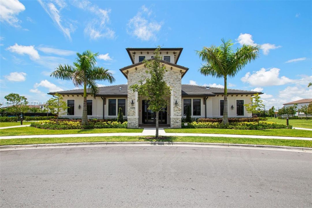 Single-story exterior featuring a stone-clad central tower, dark-toned roof shingles, manicured landscaping, and twin palm trees