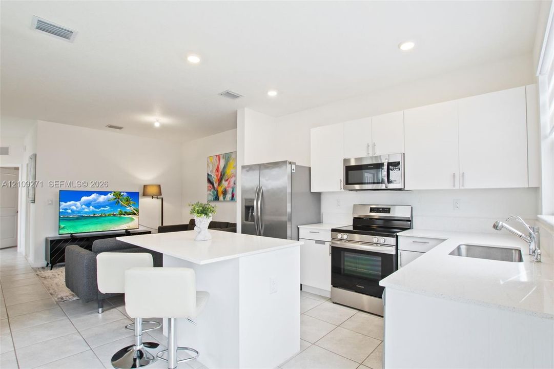 Kitchen featuring white cabinetry, solid-surface countertops, center island, recessed lighting, and stainless steel appliances