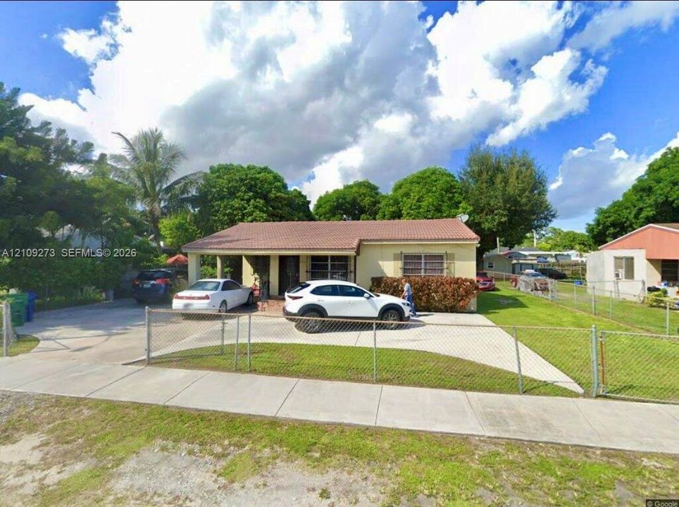 Single-story residence featuring a concrete tile roof, covered front entryway, concrete driveway, and chain-link perimeter fencing