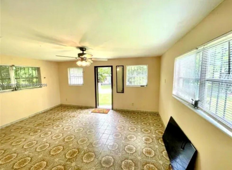 Spacious room featuring patterned tile flooring, multiple windows, and a multi-light ceiling fan