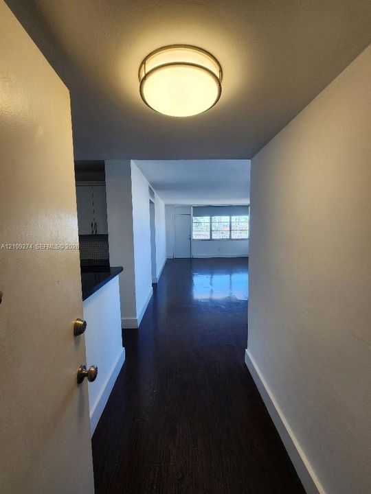 Entry featuring dark wood-finish flooring, a flush-mount circular ceiling light, and interior doorway hardware