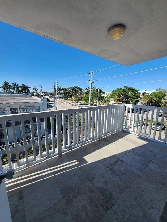 Private balcony featuring large-format tile flooring, white vertical railing, and ceiling-mounted lighting