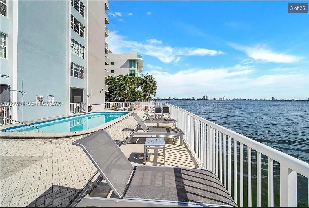 Waterfront swimming pool area featuring paver decking, a metal perimeter railing, and direct water exposure