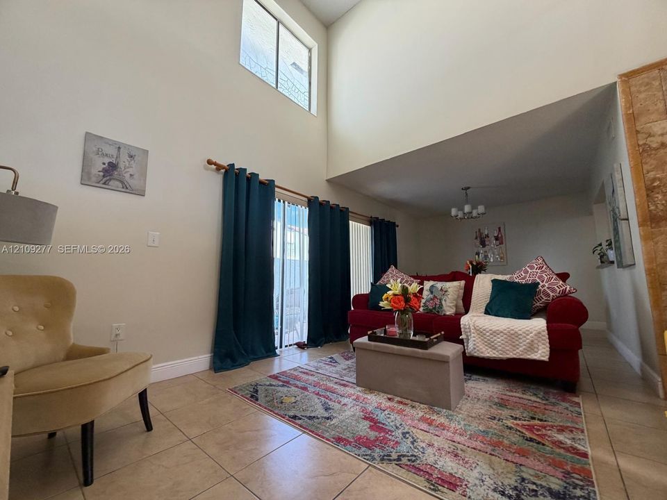 Vaulted ceiling, ceramic tile flooring, vertical sliding glass door, and multi-light chandelier