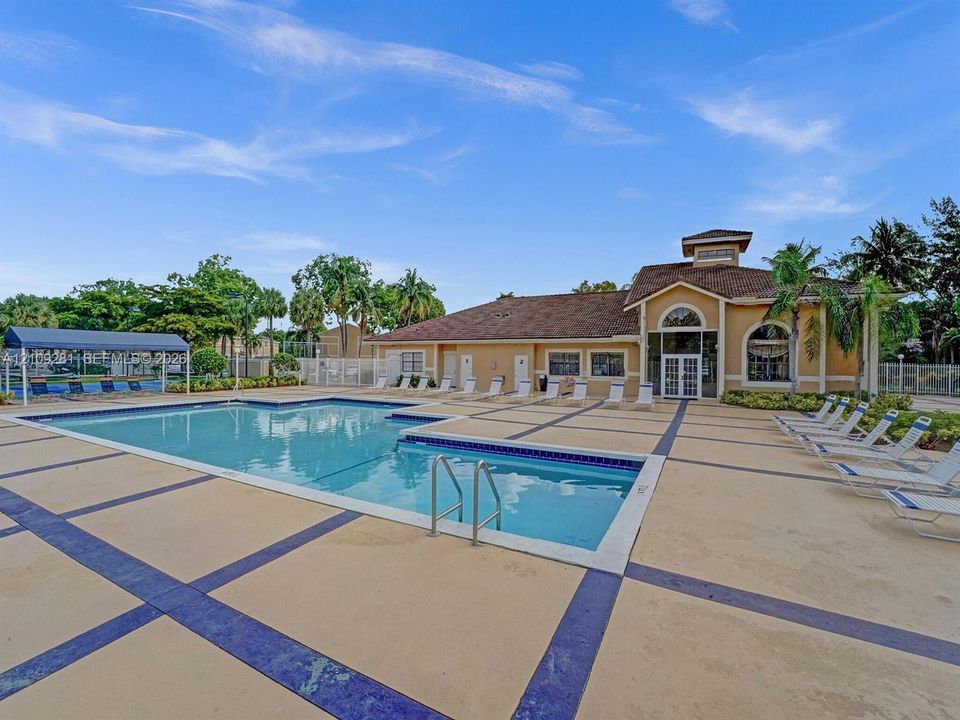 Swimming pool with tiled perimeter, expansive concrete deck with inlaid grid pattern, and covered outdoor shade structure