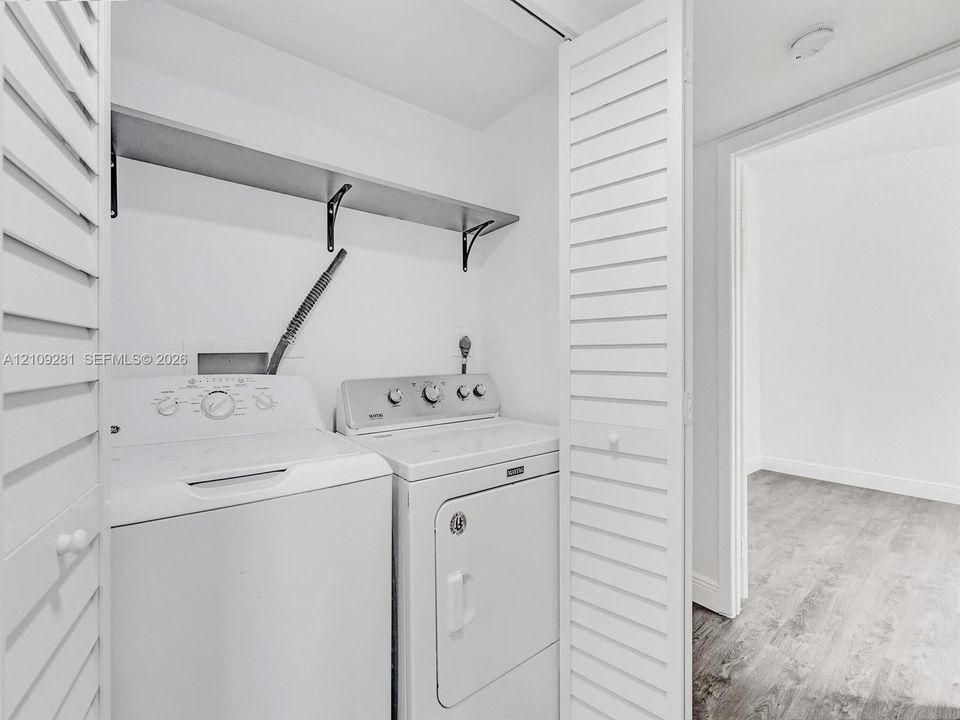 Laundry closet featuring white louvered bifold doors and a built-in upper shelving unit