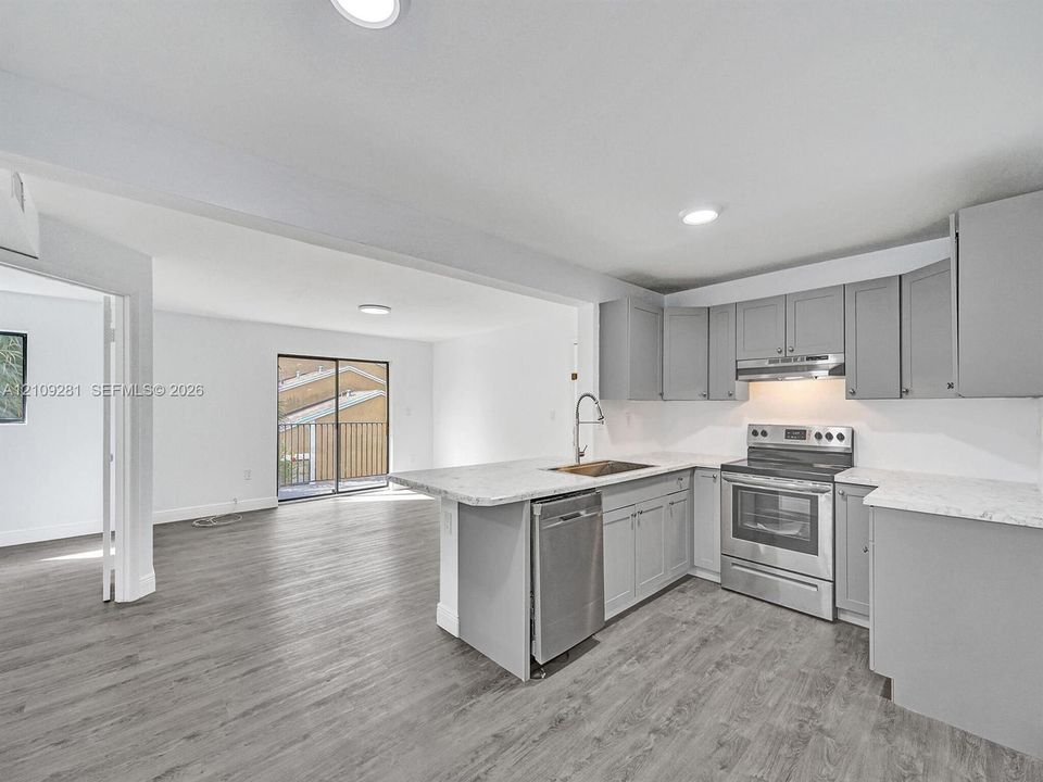 Kitchen featuring grey shaker-style cabinetry, stone-pattern countertops, stainless steel appliances, and wood-finish flooring