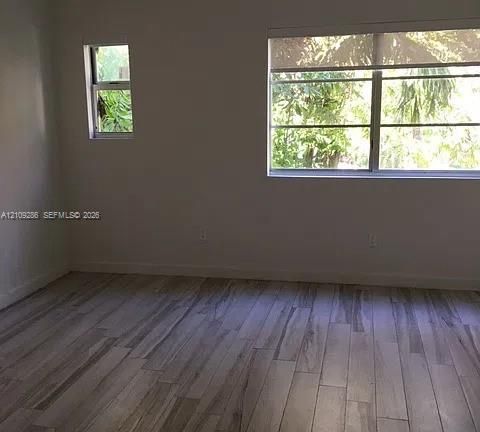 Interior space featuring wood-finish flooring, dual windows, and light-toned wall finishes