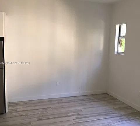Neutral-toned wood-finish flooring and a single-pane vertical window