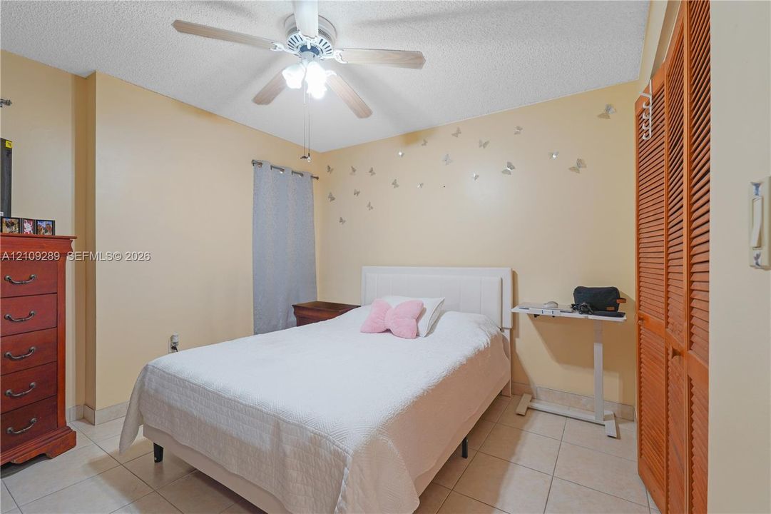 Ceramic tile flooring, ceiling fan with integrated light fixture, and wooden louvered closet doors