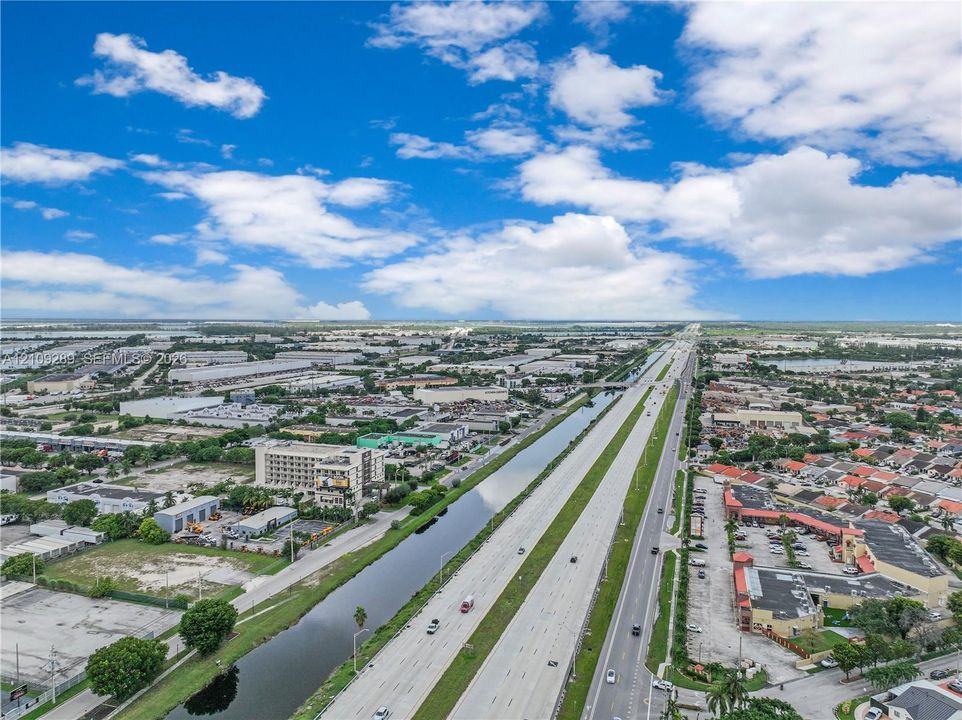 Aerial perspective featuring a multi-lane highway, paved frontage roads, and an extensive linear canal system