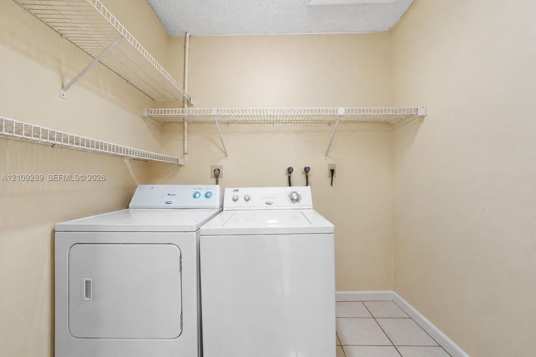 Utility space featuring white tile flooring and wall-mounted wire shelving