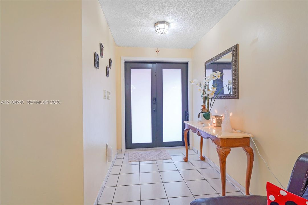 Entryway featuring double glass-paneled doors, ceramic tile flooring, and a flush-mount ceiling fixture