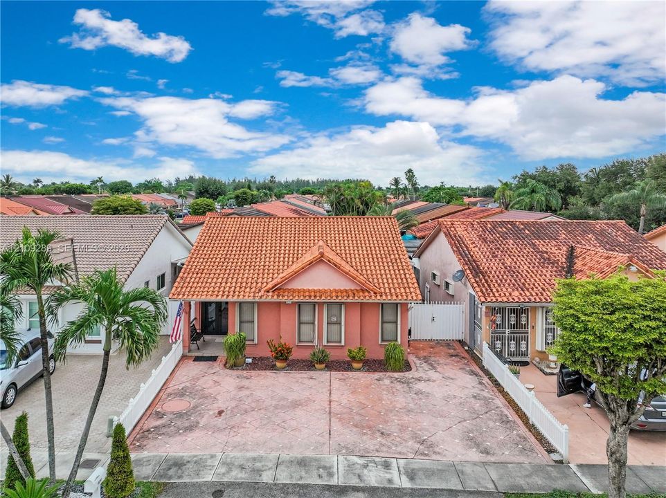 Stucco exterior featuring a clay tile roof, front-facing gable, and paved driveway