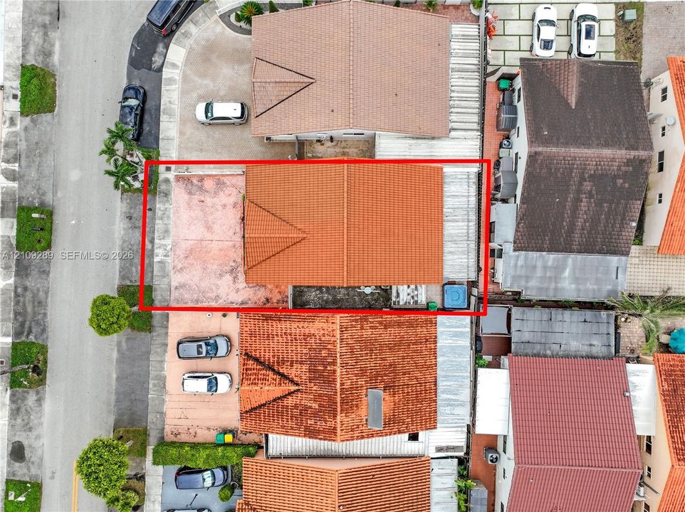 Aerial perspective of a property featuring a clay tile roof, paved driveway, and dedicated exterior space