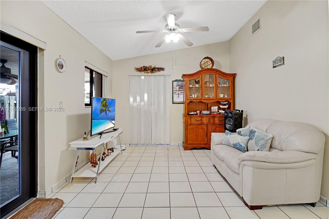 Vaulted ceiling with integrated ceiling fan, ceramic tile flooring, and sliding glass door