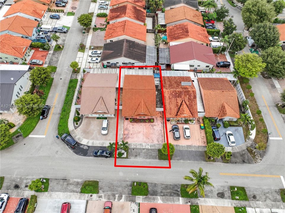 Aerial perspective of a single-story residence featuring a clay tile roof and a paved front driveway