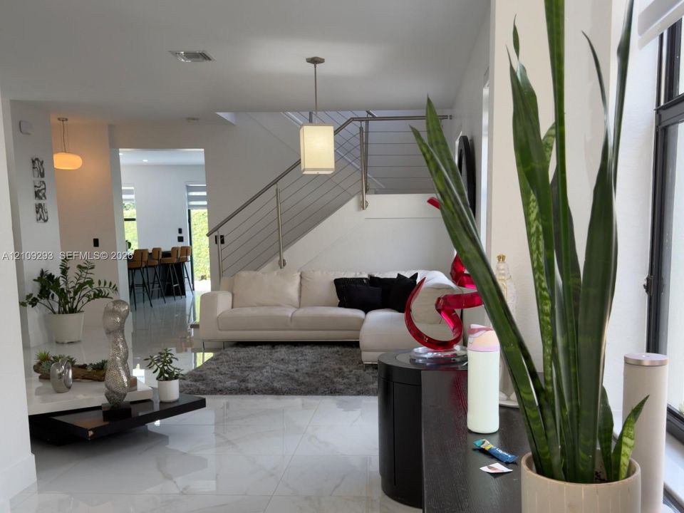 Interior featuring large-format tile flooring, a staircase with cable railings, recessed lighting, and a pendant light fixture