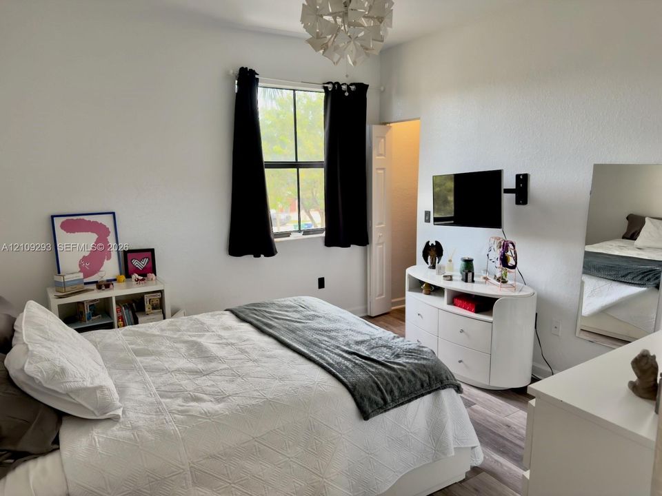 Room featuring wood-finish flooring, a multi-pane window, and a modern geometric pendant light fixture
