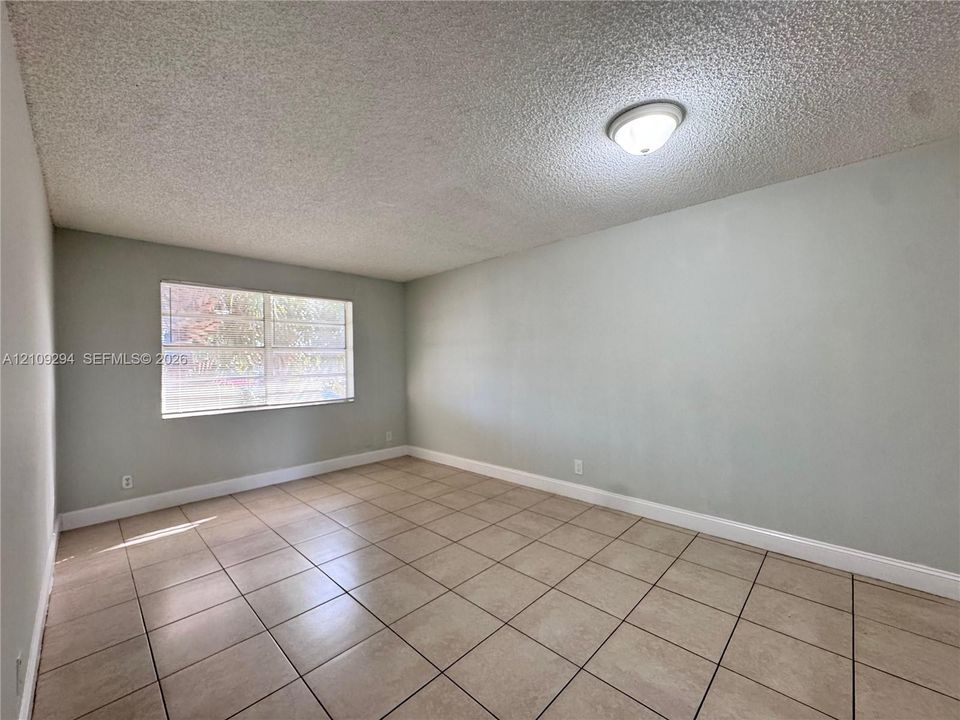 Room featuring neutral paint, large-format ceramic tile flooring, and a single-pane aluminum frame window