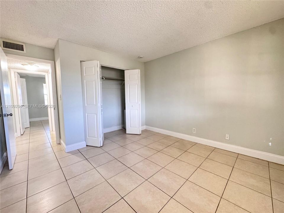 Ceramic tile flooring, neutral wall tones, and a dual-panel closet door
