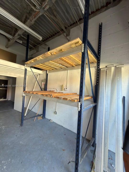 Industrial-grade steel pallet racking system with two-tier wood shelving and concrete flooring under high-clearance exposed ceilings