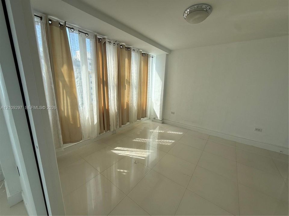 Large-format tile flooring, expansive floor-to-ceiling windows, and flush-mount overhead lighting