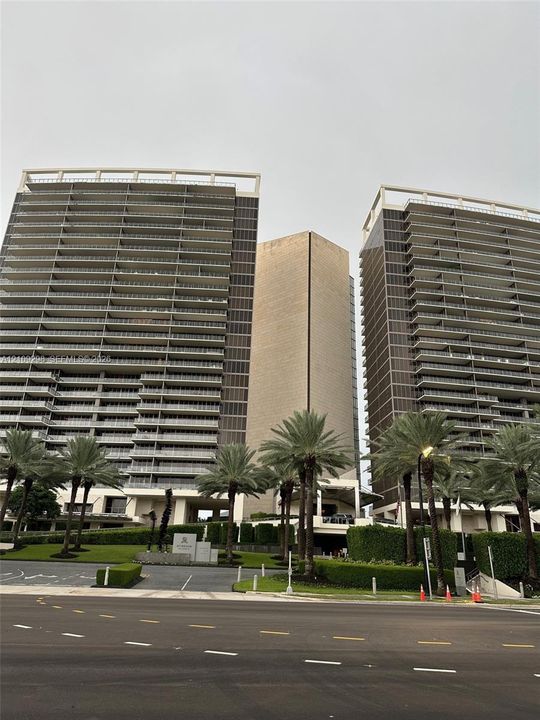 Twin high-rise towers featuring glass-paneled balconies, floor-to-ceiling windows, and manicured landscaping with mature palms