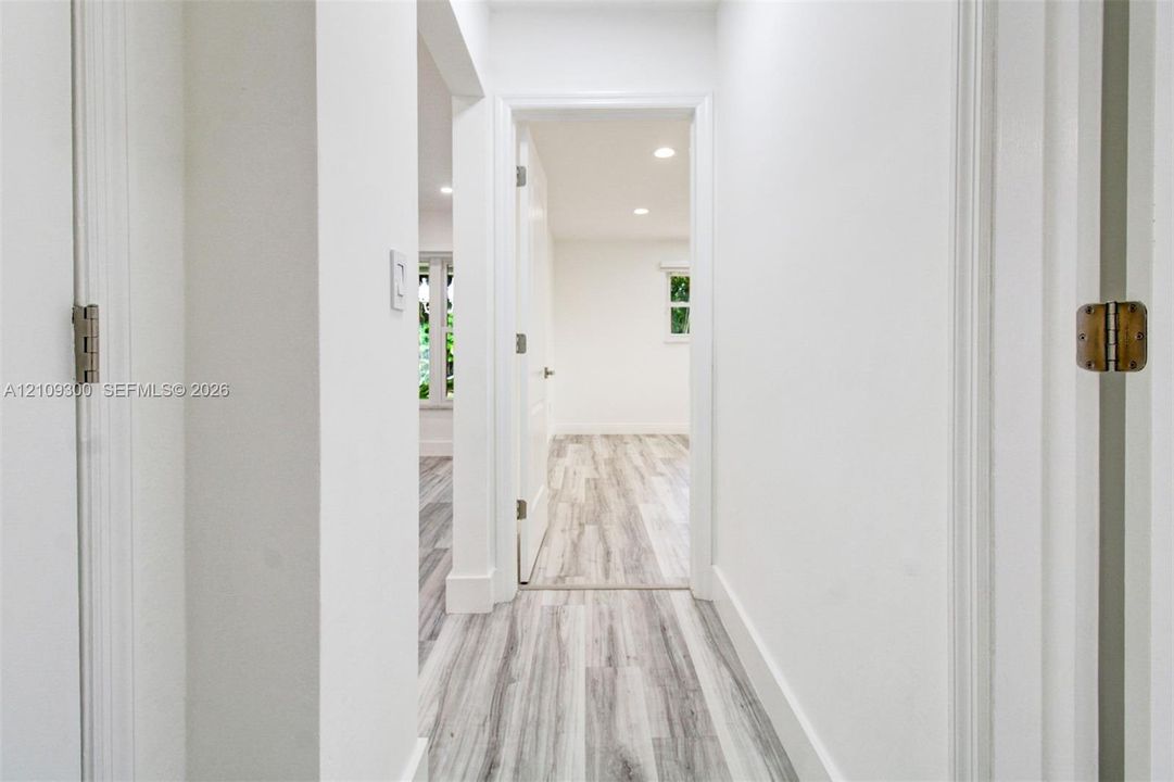 Interior hallway featuring neutral walls, wood-finish flooring, recessed lighting, and white door casings
