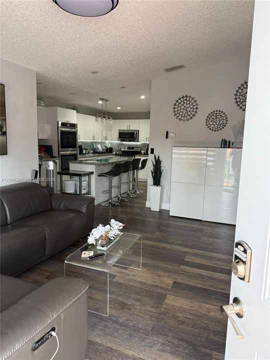 Kitchen featuring white flat-panel cabinetry, stone-finish countertops, built-in wall oven, and recessed lighting, with wood-finish flooring throughout