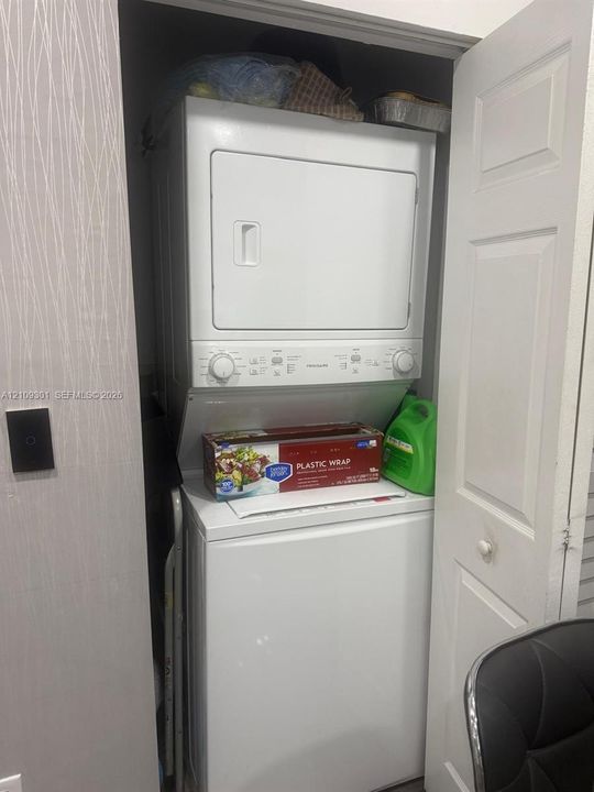 Stacked laundry appliance configuration housed within a dedicated closet featuring a bi-fold door