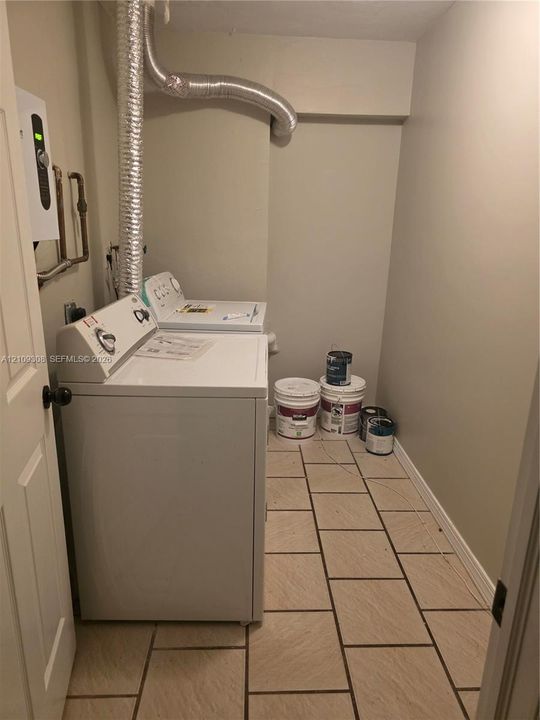 Laundry area featuring tile flooring, neutral walls, and a wall-mounted unit