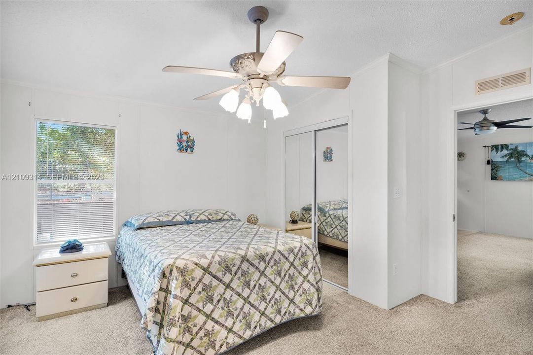 Neutral interior room featuring neutral carpeting, a ceiling fan with integrated lighting, and a closet with sliding mirrored doors
