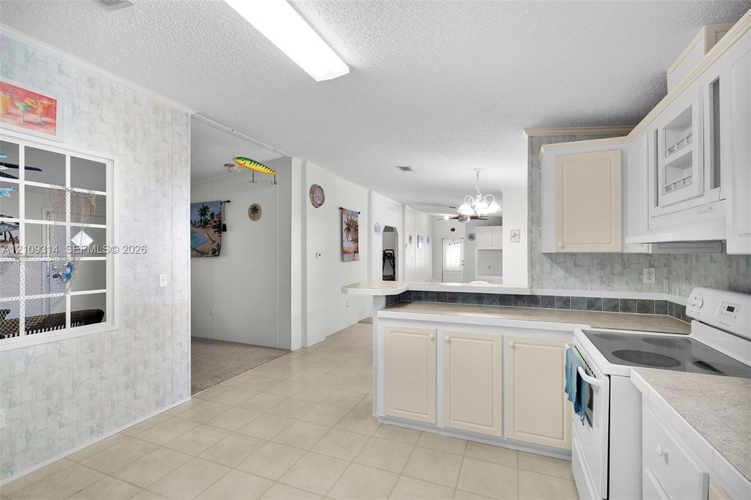 Kitchen featuring white cabinetry, solid-surface countertops, tile backsplash, and a breakfast bar