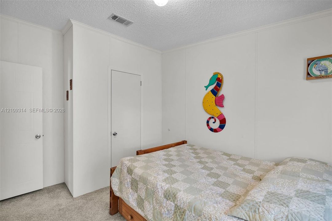 Neutral-toned carpeting, white wall paneling, ceiling-mounted light fixture, and two interior doors with brushed metal hardware