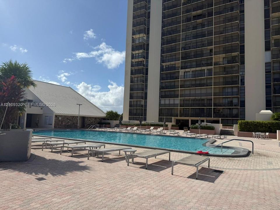 Expansive swimming pool with integrated stair entry, surrounded by patterned paver decking and stone-accented perimeter structure