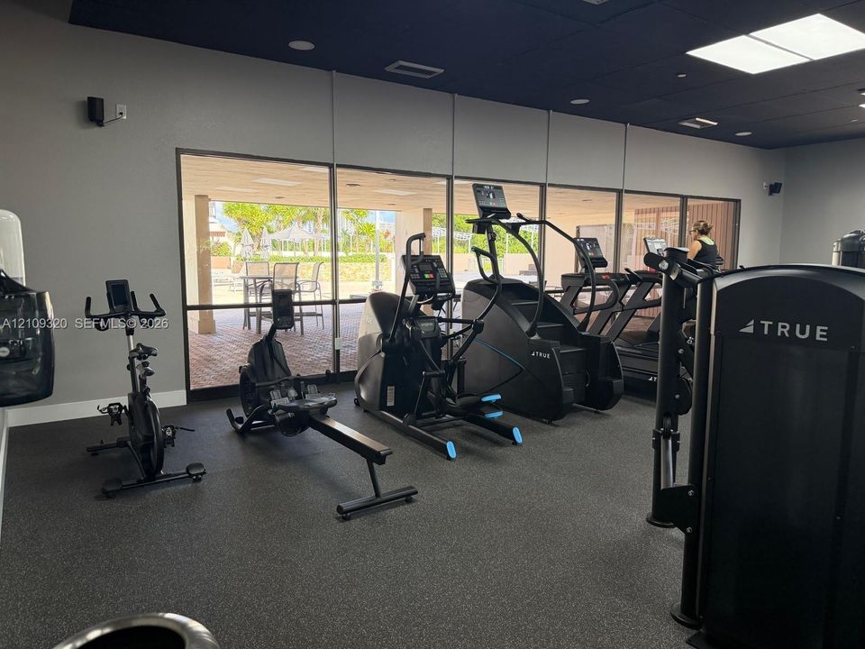 Fitness facility featuring rubberized flooring, ceiling-mounted lighting, and expansive floor-to-ceiling windows