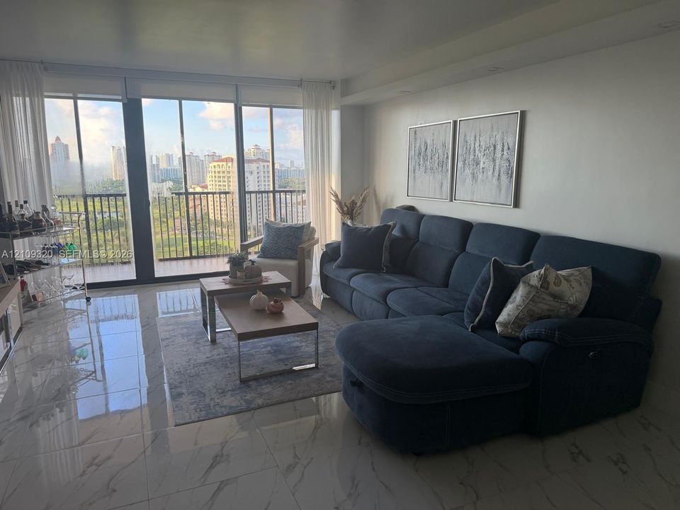 Floor-to-ceiling windows, polished stone-finish flooring, and a private balcony featuring a metal railing