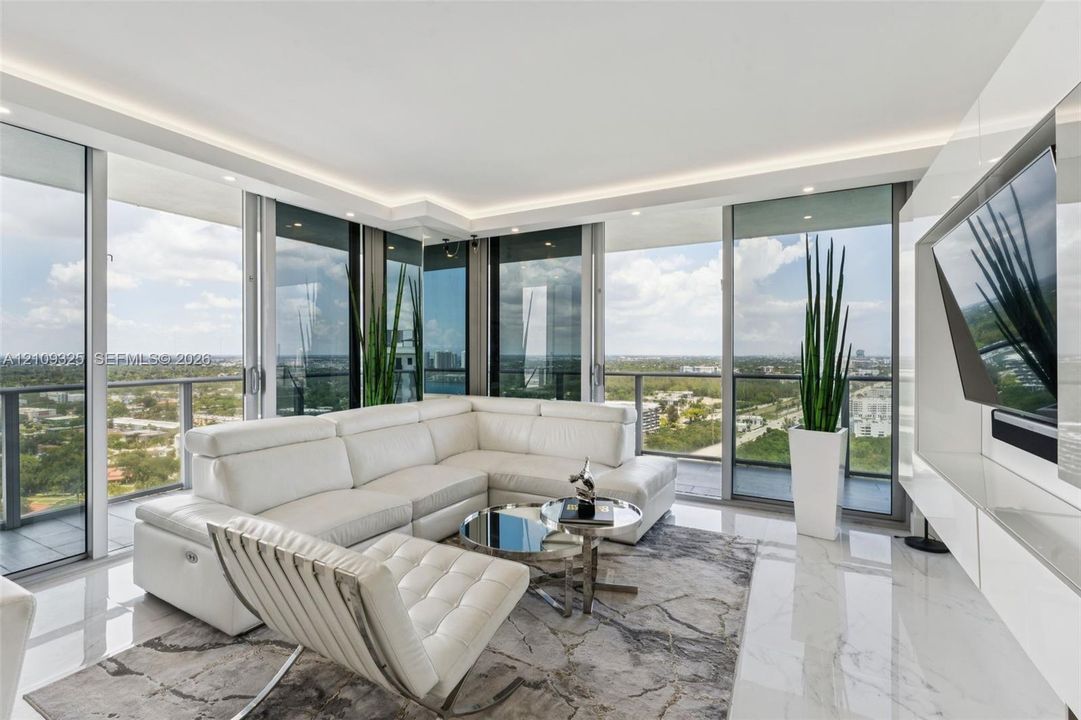 Floor-to-ceiling glass walls, polished stone flooring, recessed ceiling lighting, and built-in high-gloss wall cabinetry