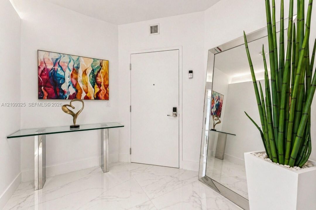 White tile flooring featuring neutral veining, high-contrast white walls, and integrated recessed ceiling lighting