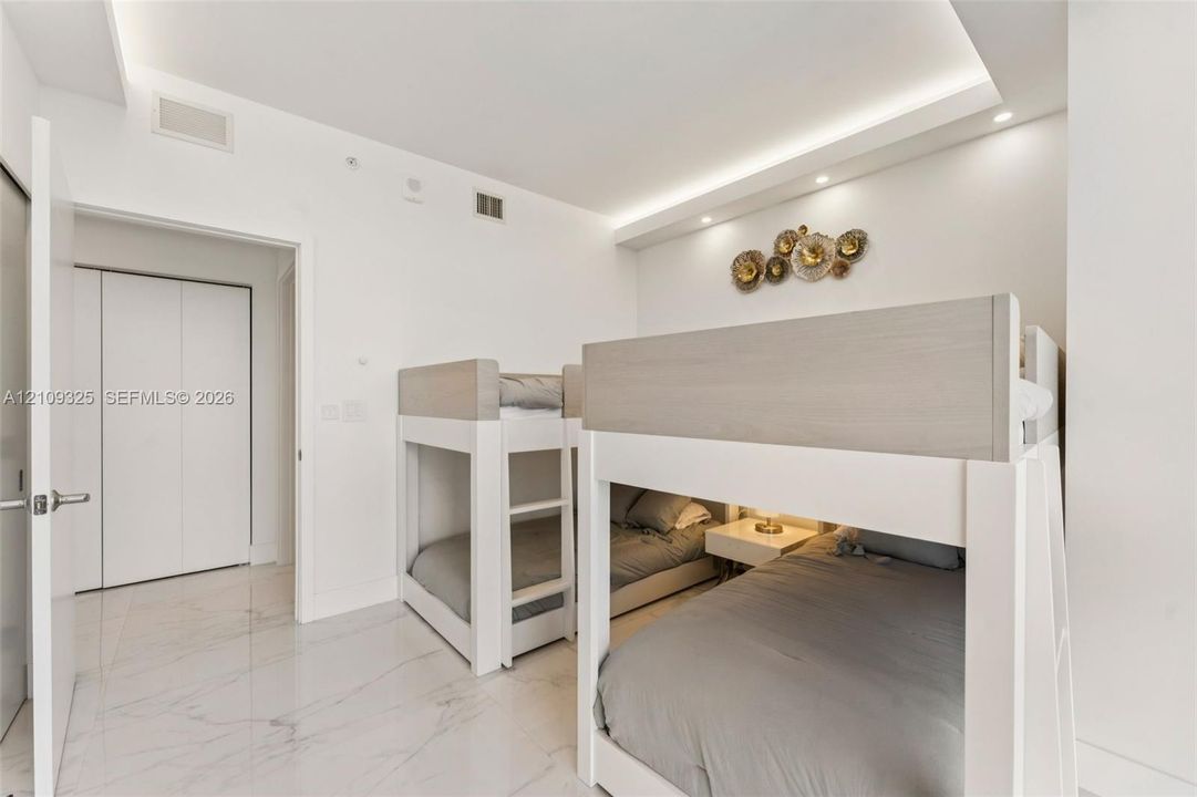 Interior space featuring polished stone-finish flooring, recessed tray ceiling lighting, and double-door closet storage