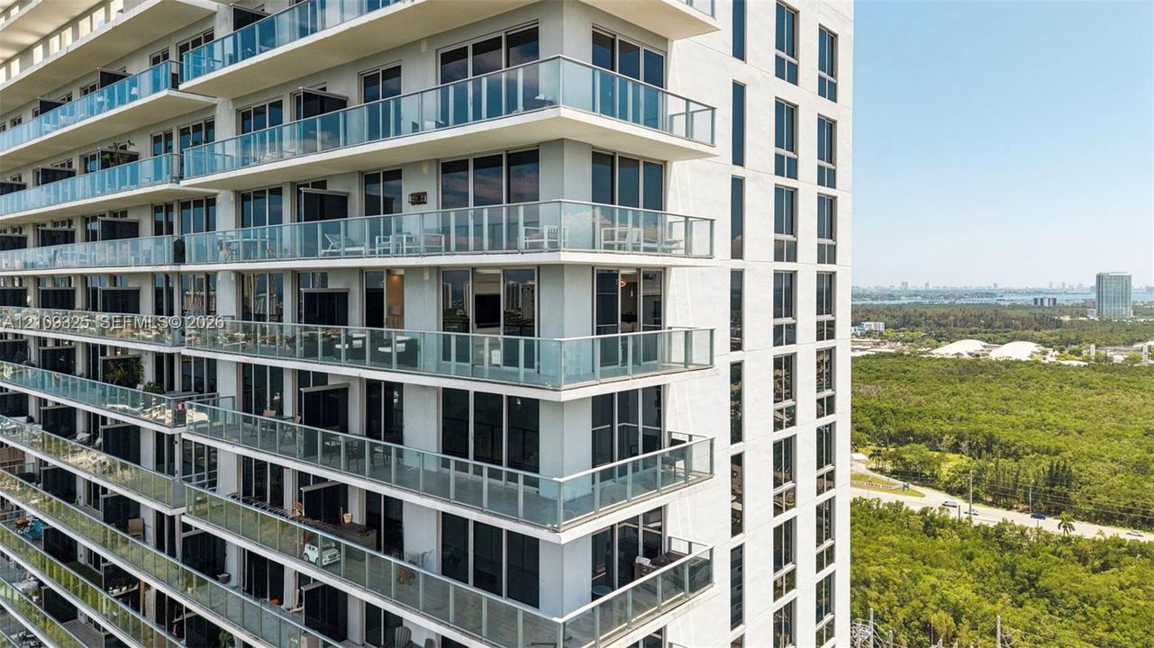 High-rise exterior featuring glass balcony railings, floor-to-ceiling windows, and concrete structural columns