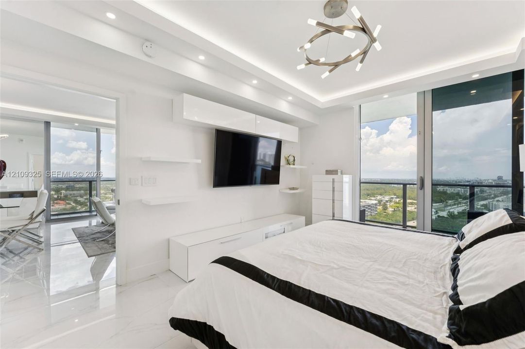 Floor-to-ceiling glass windows, recessed ceiling lighting with crown molding, custom built-in cabinetry, polished stone-finish flooring, and modern geometric chandelier